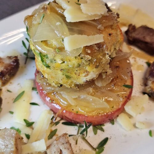 Kürbis Knödel mit Fetakäse und gebratenen Apfelscheiben, angerichtet mit frischem Thymian und Parmesan auf einem rustikalen Teller.