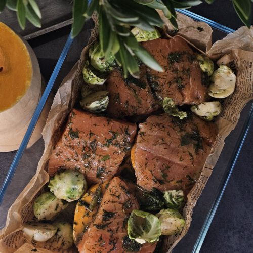 Lachs mit Kürbis in Orangensauce, angerichtet mit Rosenkohl, frischen Kräutern und knusprigen Nüssen – herbstliche Farben auf einem Teller.