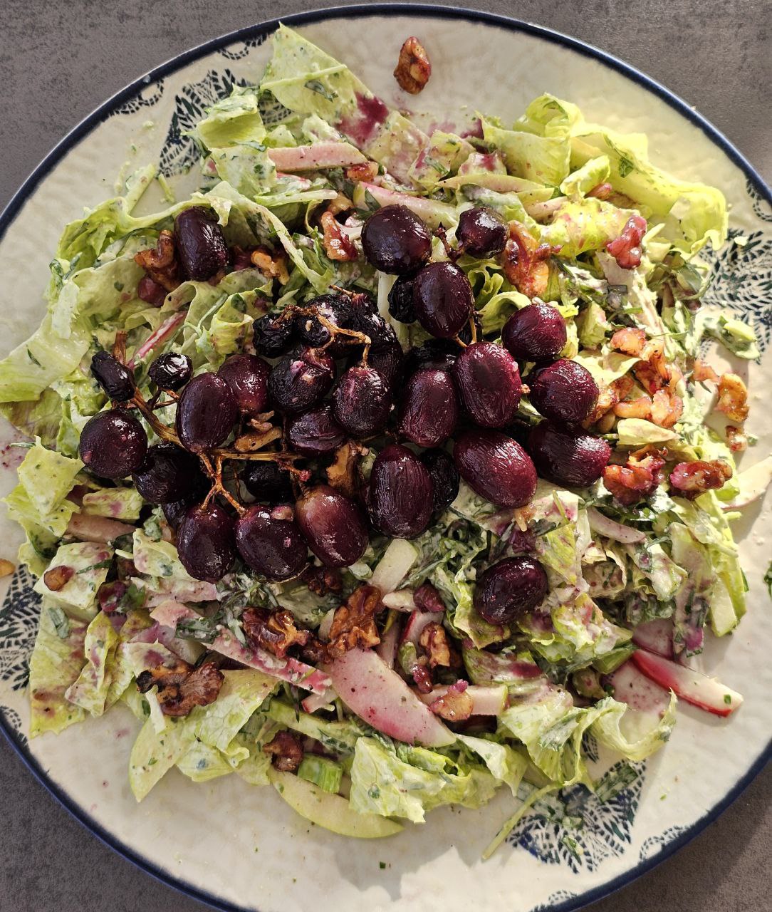 Gegrillter Trauben-Walnuss-Salat mit Estragon-Joghurt-Dressing, garniert mit karamellisierten Trauben und knusprigen Walnüssen, serviert auf einem Bett aus frischem Römersalat, Sellerie, Apfelscheiben und Radieschen.