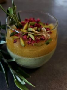 Pistazien-Zitronen Panna Cotta in einem Glas, garniert mit gehackten Pistazien und Zitronenschale.