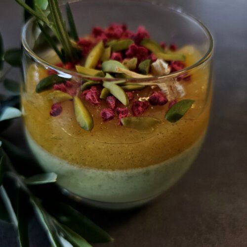 Pistazien-Zitronen Panna Cotta in einem Glas, garniert mit gehackten Pistazien und Zitronenschale.
