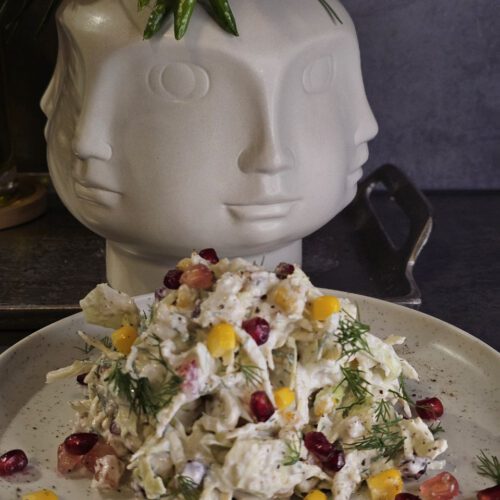 Krautsalat mit Hähnchenbrust, Granatapfelkernen und Walnüssen, serviert in einer Schüssel – gesunde und farbenfrohe Mahlzeit mit cremigem Joghurtdressing
