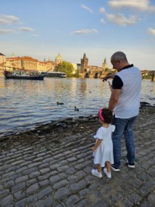 Karlsbrücke in Prag bei Sonnenuntergang mit Gaslaternen und Moldau im Hintergrund.