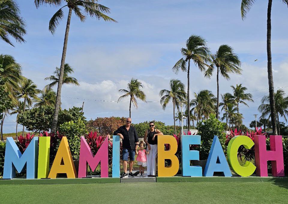 a group of people standing in front of a sign Miami Beach