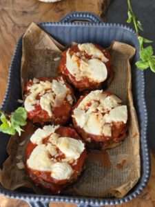 Einzelne Portionen der Parmigiana di Melanzane mit Mozzarella und Parmesan in der Backform vorbereitet
