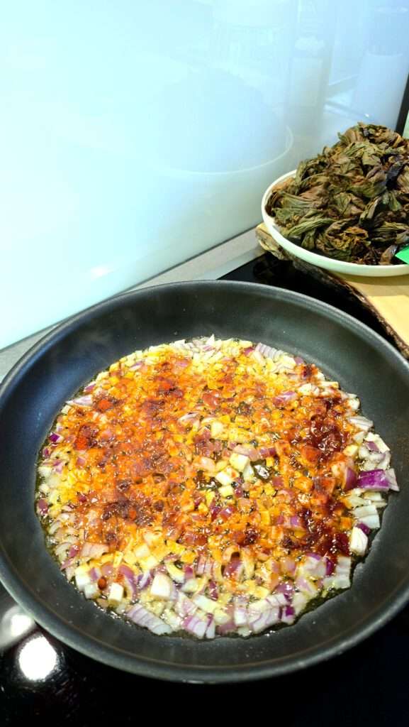 Rote Zwiebeln mit Paprikapulver werden für den Aveluk-Salat angedünstet