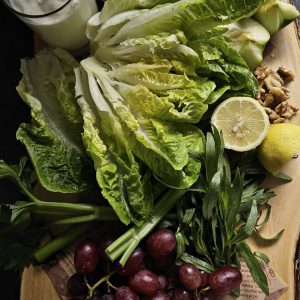 Gegrillter Trauben-Walnuss-Salat mit Estragon-Joghurt-Dressing, garniert mit karamellisierten Trauben und knusprigen Walnüssen, serviert auf einem Bett aus frischem Römersalat, Sellerie, Apfelscheiben und Radieschen.