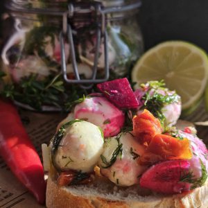 Marinierte Mozzarella oder Feta in einer aromatischen Kräutermarinade mit Olivenöl, Knoblauch und getrockneten Tomaten, serviert als Antipasti auf einem frischen Baguette – perfekt als Beilage zum Grillen oder für gesunde Snacks.