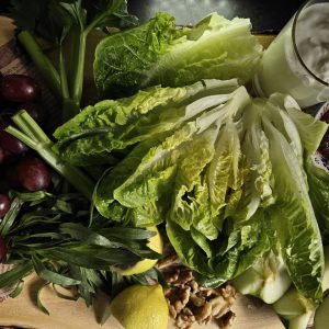 Gegrillter Trauben-Walnuss-Salat mit Estragon-Joghurt-Dressing, garniert mit karamellisierten Trauben und knusprigen Walnüssen, serviert auf einem Bett aus frischem Römersalat, Sellerie, Apfelscheiben und Radieschen.