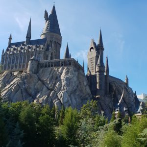 Das Hogwarts-Schloss im Themenpark The Wizarding World of Harry Potter, Universal Studios Orlando, umgeben von üppiger Vegetation unter blauem Himmel