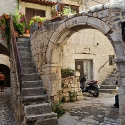 Enge, gepflasterte Gassen in der Altstadt von Trogir, Kroatien, gesäumt von historischen Steinhäusern und charmanten Cafés.