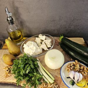 Zucchini-Birnen-Salat mit cremigem Feta-Dressing, serviert mit frischen Kräutern und gehackten Walnüssen.