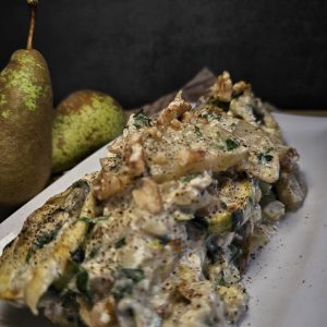 Zucchini-Birnen-Salat mit cremigem Feta-Dressing, serviert mit frischen Kräutern und gehackten Walnüssen.