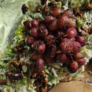 Gegrillter Trauben-Walnuss-Salat mit Estragon-Joghurt-Dressing, garniert mit karamellisierten Trauben und knusprigen Walnüssen, serviert auf einem Bett aus frischem Römersalat, Sellerie, Apfelscheiben und Radieschen.